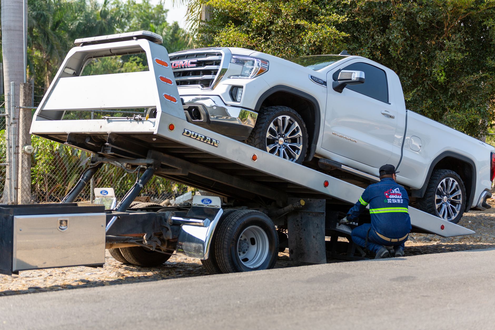 A Snappy Towing professional operator securing a vehicle onto a flatbed tow truck on a suburban street in Lenexa, Kansas, with safety lights flashing.